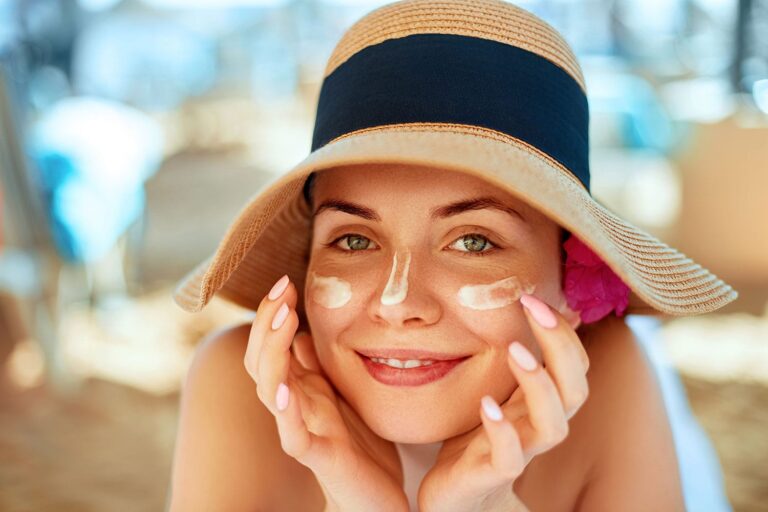 Soothing sunburn, Young pretty woman applying sun cream and touch own face.