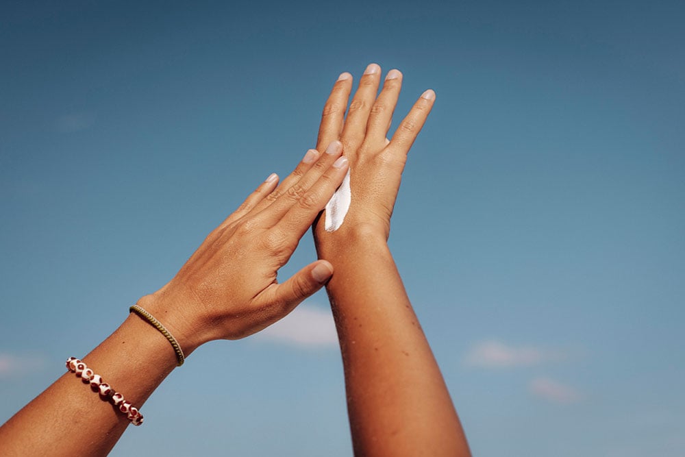 Beauty Blog Applying Sun Cream Under Clear Blue Sky stock photo