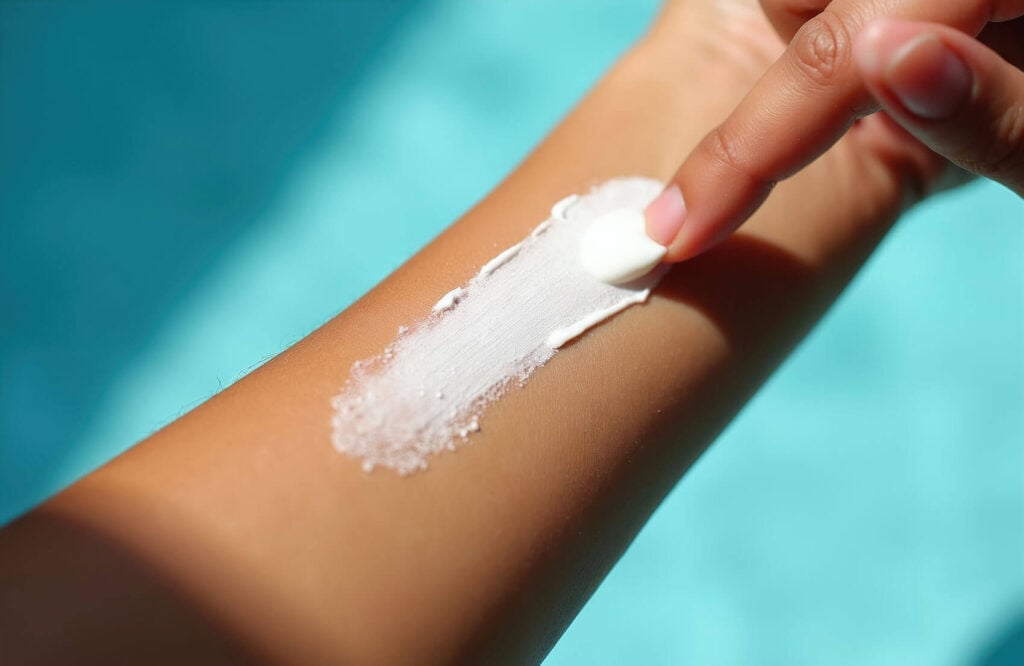 Beauty Blog Finger spreads white mineral sunscreen cream on arm. Smooth application ensures healthy skin care