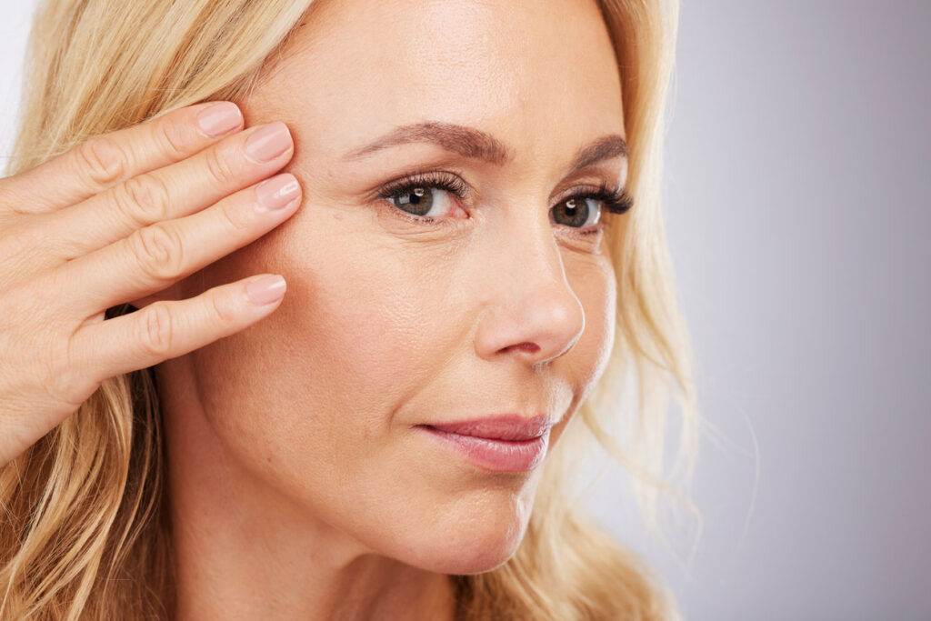 Beauty Blog Face, skincare and antiaging with a mature woman in studio on a gray background for natural beauty