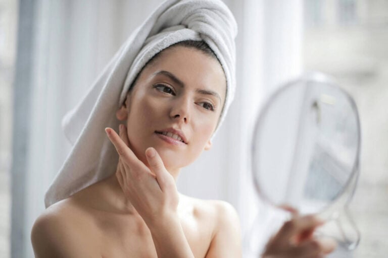 Photo of Woman With a Towel on her Head Looking in the Mirror
