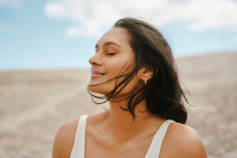 Woman With Glowing Skin Enjoying a Peaceful Breeze in a Serene Natural Setting