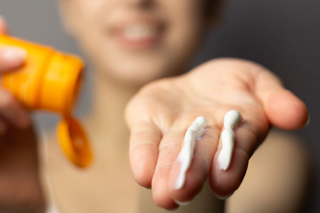 Beauty Blog Young woman applying the correct amount of sunscreen for face and neck