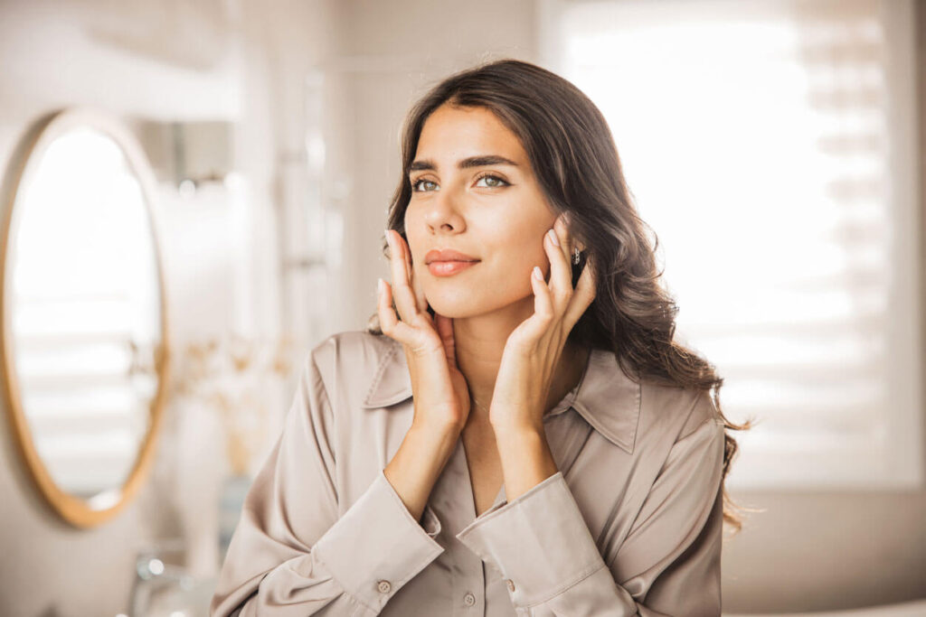 Portrait of young woman with smooth face skin looking at mirror stock photo