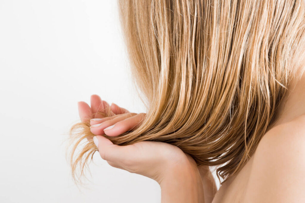 Beauty Blog Young woman with hand touching her wet blonde perfect hair