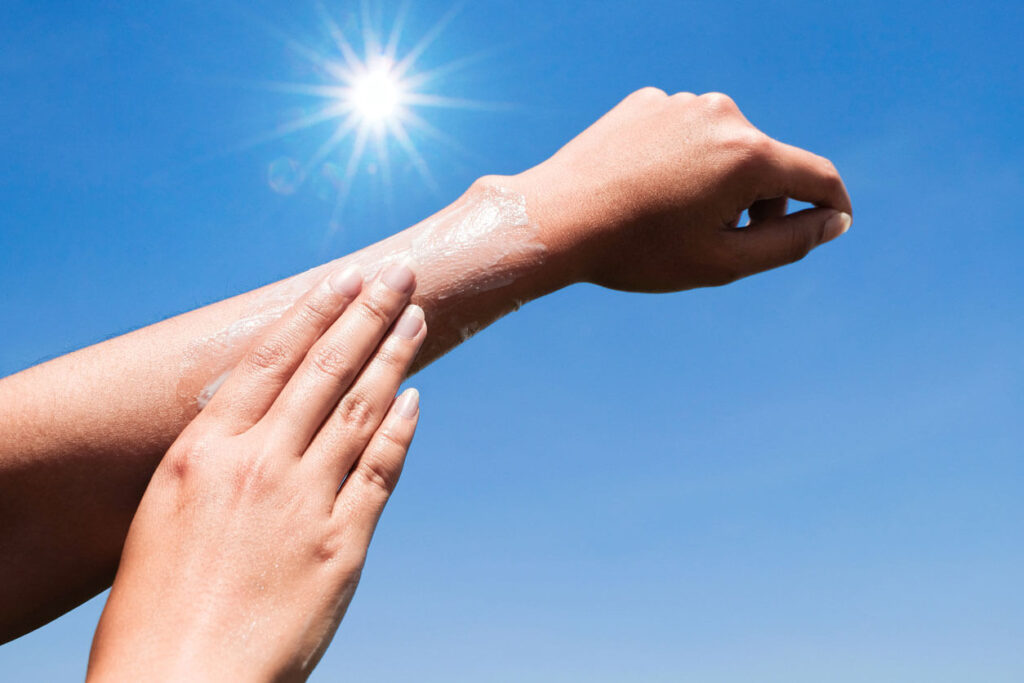Beauty Blog Hand of female holding sunscreen. sun light Sky background