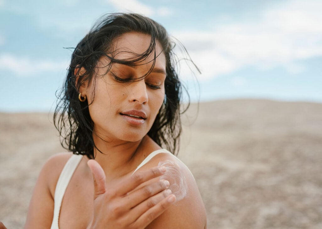 Beauty Blog Young Woman Applying Sunscreen Under a Clear Blue Sky in a Sunny Outdoor Setting stock photo