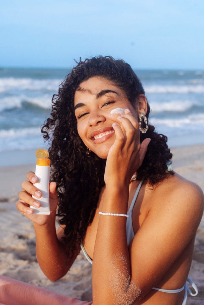 Beauty Blog Young woman applying sunscreen on her face at the beach stock photo