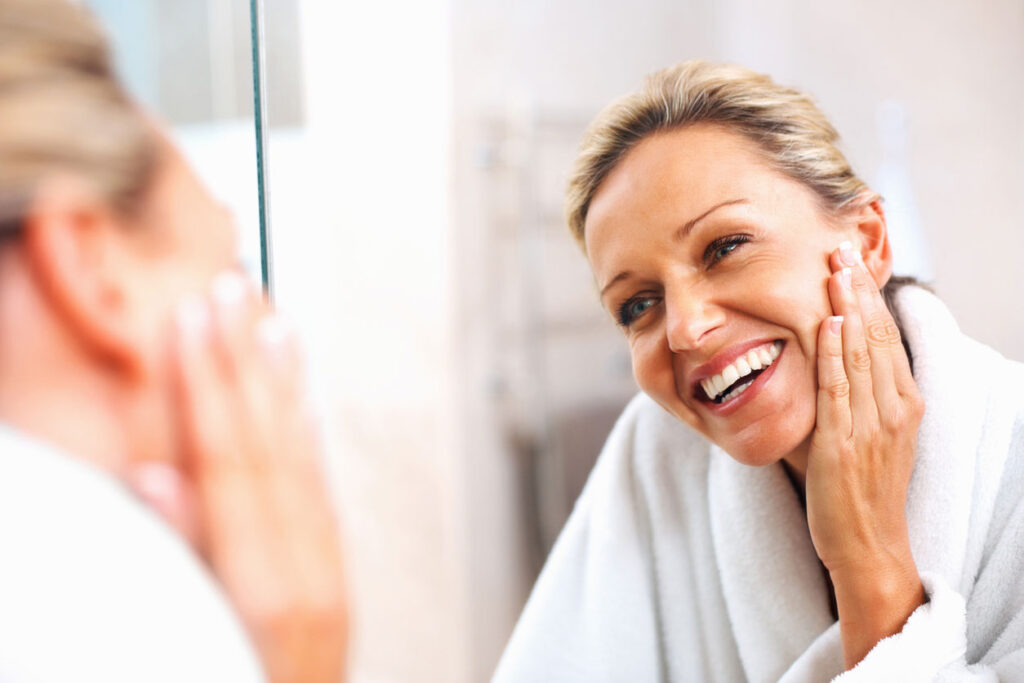 Beauty Blog Happy mature woman admiring herself in the mirror stock photo