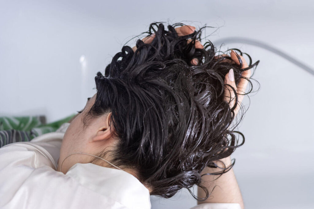 Hair Care Woman washing curly hair in shower for self-care routine