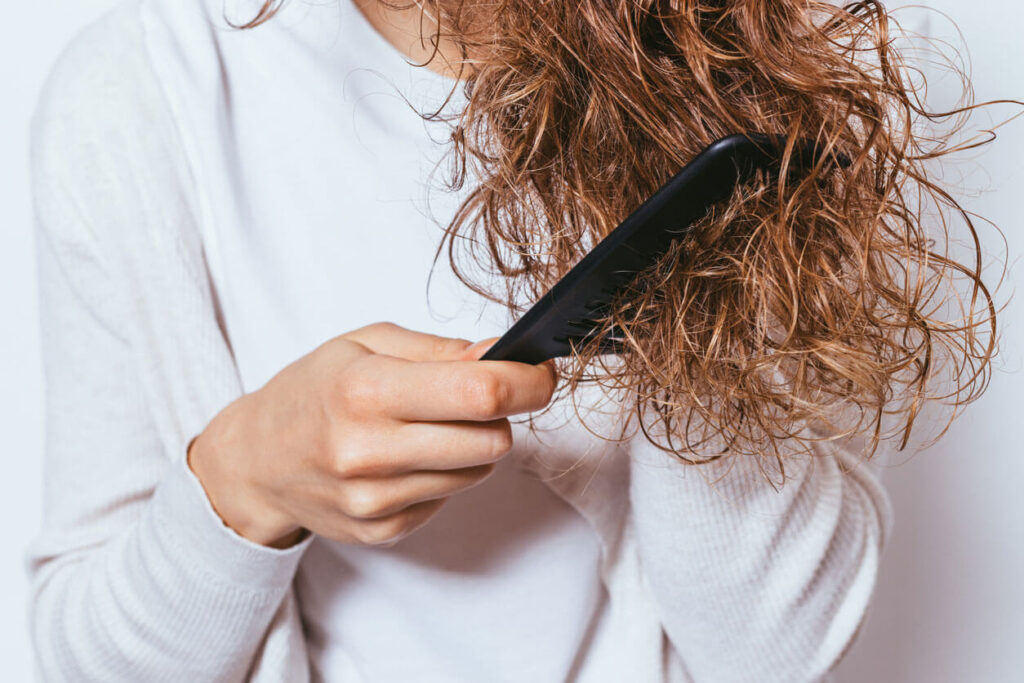 Hair Care Young woman wearing white shirt combing hair
