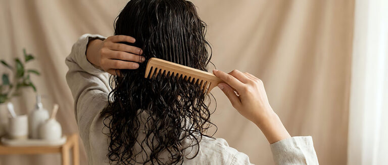 Young woman with long curly dark hair combing wet hair with wooden comb stock art