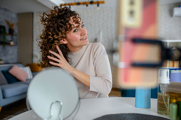 Curly Hair Influencer Demonstrating Blow Drying Technique stock photo