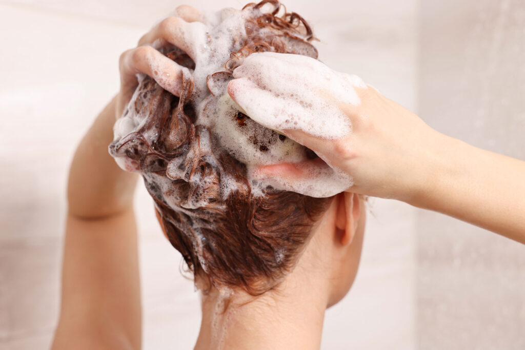 Beauty Blog Young woman washing her hair and wondering how often to use clarfying shampoo