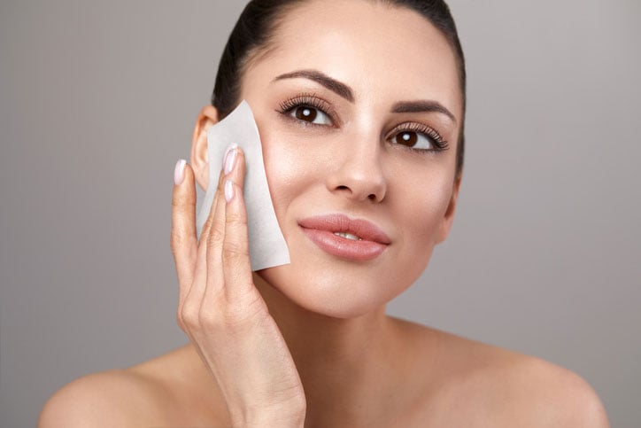 Beauty Blog Young woman removing oil from face using blotting papers stock photo